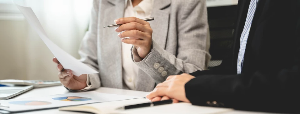 Sc&egrave;ne d'int&eacute;rieur professionnel avec deux personnes travaillant sur des documents financiers