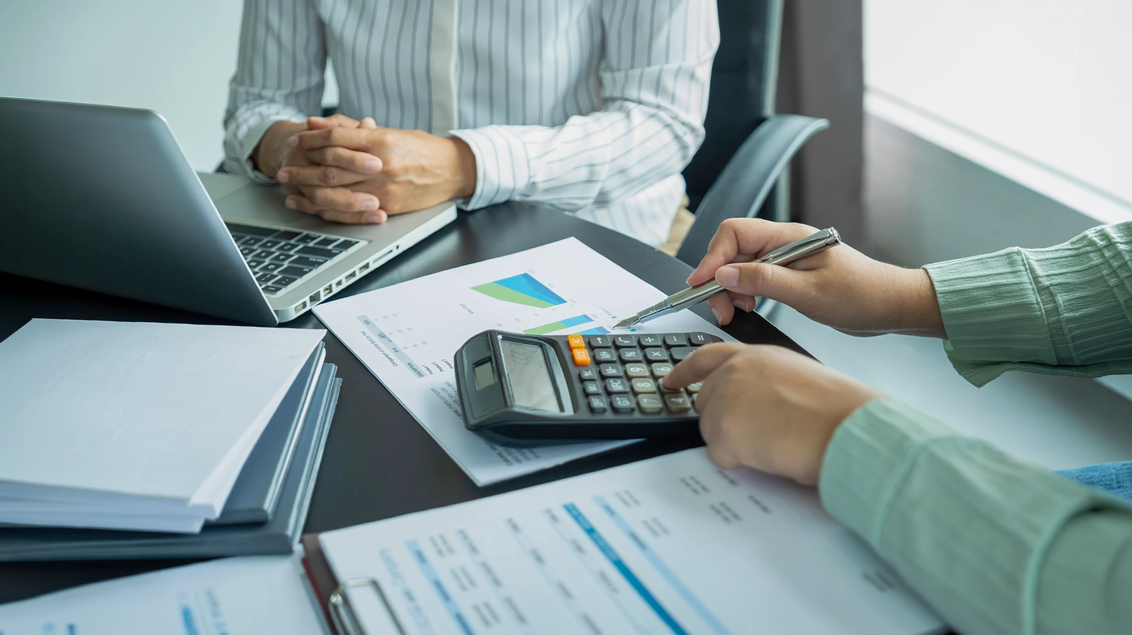 R&eacute;union d'affaires dans bureau moderne avec deux hommes en costume analysant des rapports financiers